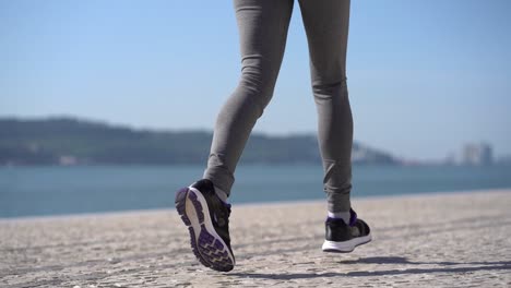 Legs-of-sporty-young-woman-running-at-riverside